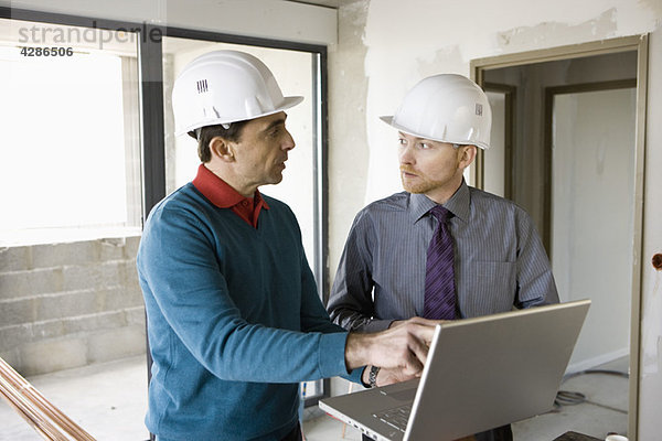Bauunternehmer und Geschäftsmann mit Laptop auf der Baustelle