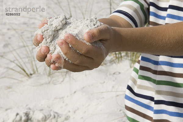 Kind schaufelt Sand mit den Händen