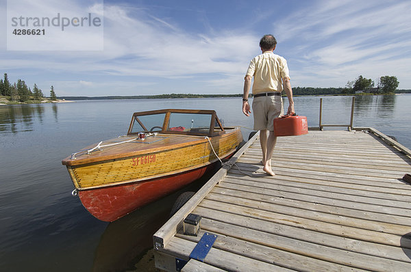 Mann zu Fuß mit Gas kann in Richtung Mahagoni Motorboot  Gunn Lake  Ontario