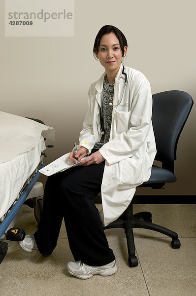 Ärztin neben Krankenhausbett mit Patienten Diagramms in Krankenhaus Untersuchungsraum  Toronto  Ontario