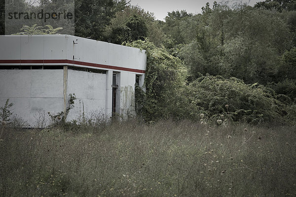 Eine alte heruntergekommen und verlassenen Tankstelle in überwucherten Feld