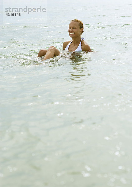 Frau im Flachwasser sitzend