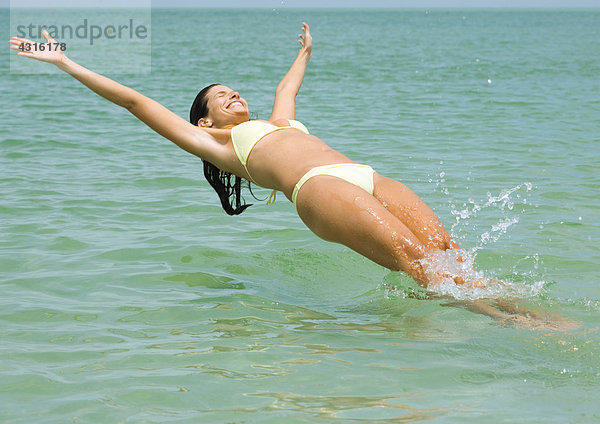 Frau springt rückwärts ins Meer.