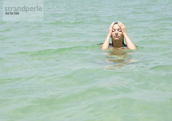 Frau im Meer  Hände auf dem Kopf