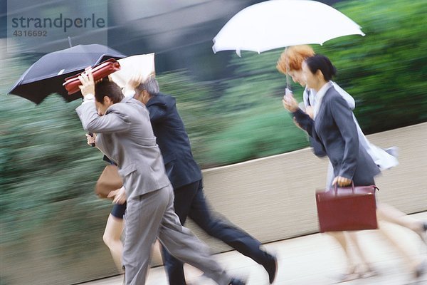 Gruppe von Führungskräften eilt durch den Regen