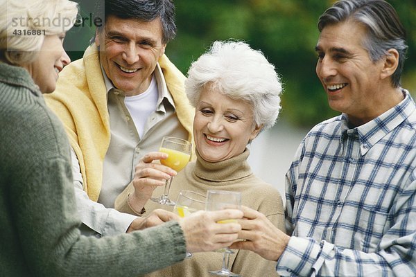 Zwei ältere Paare  die Orangensaft trinken und reden.