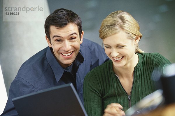 Junge Frau und Mann mit Laptop  lächelnd