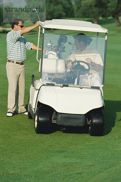 Golfer  der den Golfschläger vom Golfwagen nimmt