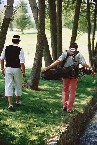 Golfer auf der Suche nach einem Ball unter Bäumen  Rückansicht