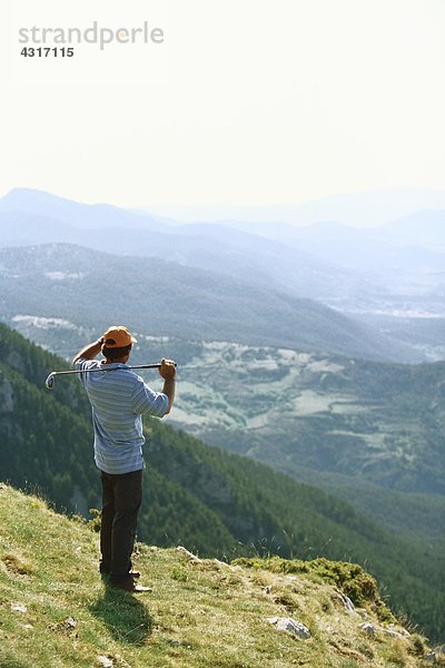 Golfer stehend  mit Blick auf die Berglandschaft