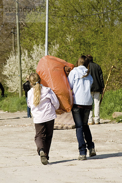 Mädchen  die zusammen Müllsack tragen
