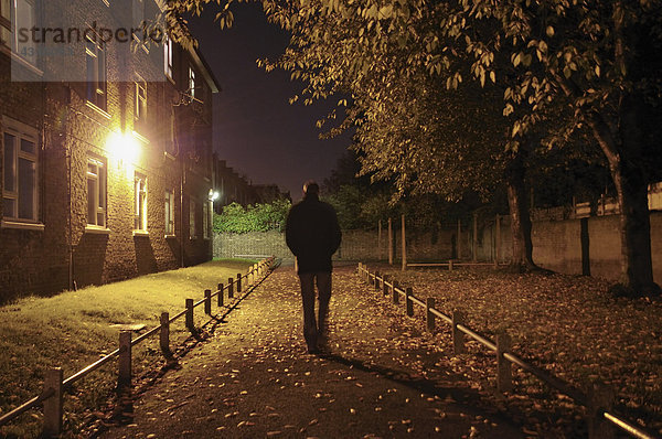 Männlicher Spaziergang entlang der Gasse bei Nacht