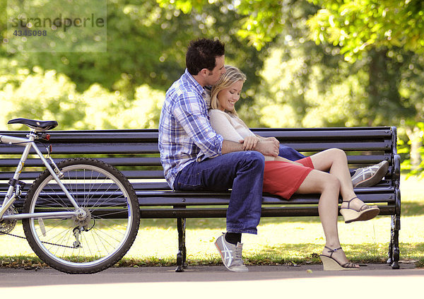Junges Paar entspannt sich gemeinsam auf der Parkbank