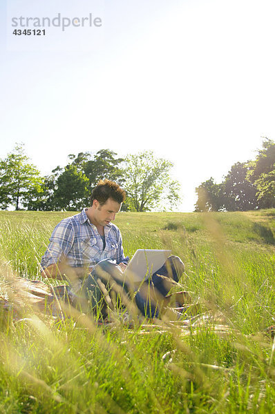 Junger Mann mit Laptop im Park