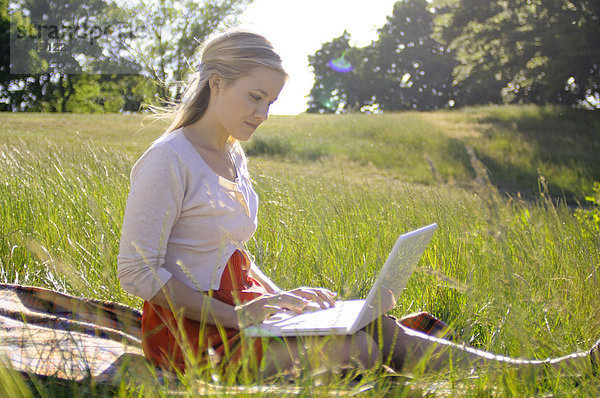 Junge Frau mit Laptop im Park