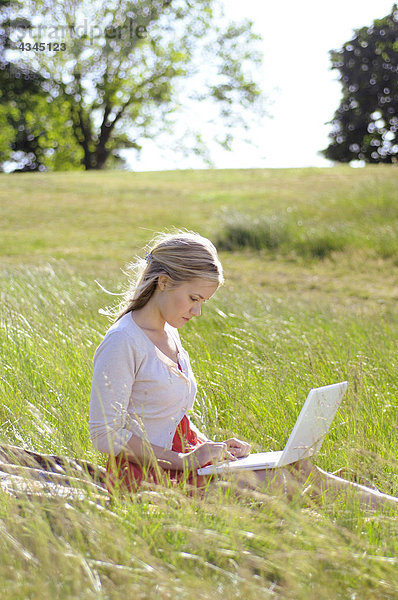 Junge Frau mit Laptop im Park