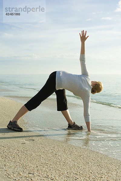 Frau beim Yoga am Strand