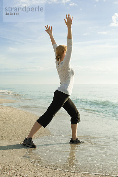 Frau beim Yoga am Strand