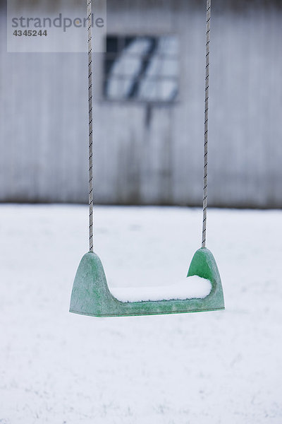 Spielplatzschaukel mit Schnee bedeckt