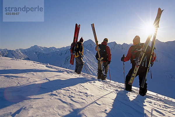 3 Extremskifahrer stehen auf Ridge mit Blick auf Turnagain Arm Chugach CT in South Central Alaska Winter sun