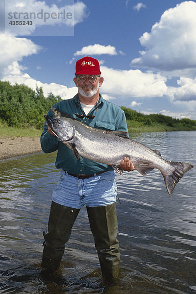 Fischer hält große Königlachse an Uferlinie Nushagak River Südwesten AK Sommer