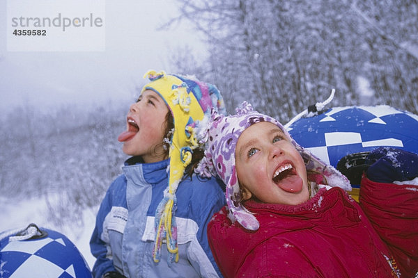 Junge Mädchen fangen Schneeflocken auf ihren Zungen während Sie Rodeln Girdwood Alaska South Central Winter