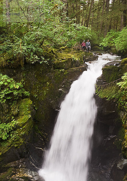 Zwei Wanderer stehen an der Spitze der Sägewerk Creek Falls im Tongass National Regenwald in der Nähe von Juneau  Alaska Southeast