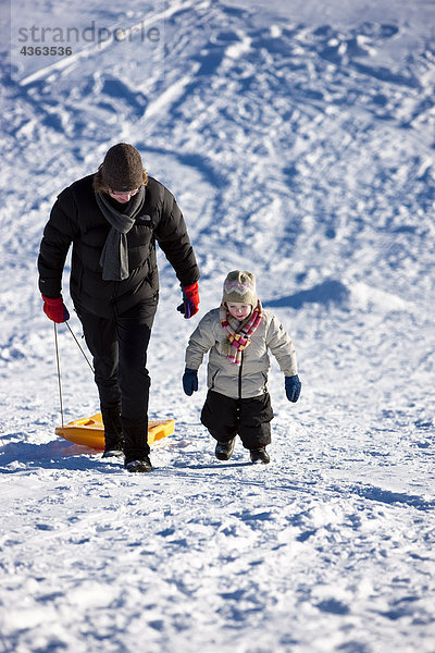 Mutter und Tochter Wandern bergauf Schlitten nach Schlitteln entlang es während der Winter  Anchorage  South Central Alaska