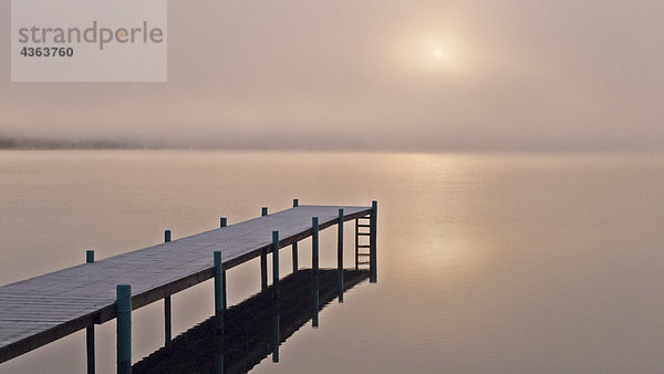 Ein nebelig Sonnenaufgang über ein Dock in Lake Whatcom während des Winters  Bellingham  Washington  USA