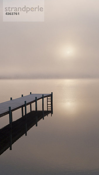 Ein nebelig Sonnenaufgang über ein Dock in Lake Whatcom während des Winters  Bellingham  Washington  USA