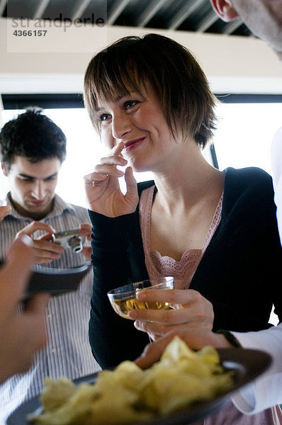 Junge lächelnde Frau mit Glas Champagner  Mann mit Digitalkamera im Hintergrund