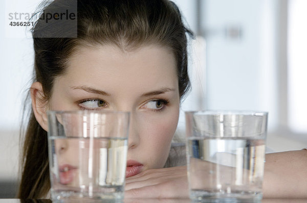 Porträt einer jungen Frau beim Anblick von 2 Gläsern Wasser