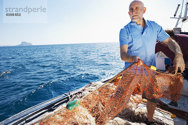 Fischer auf dem Boot beim Einholen von Netzen