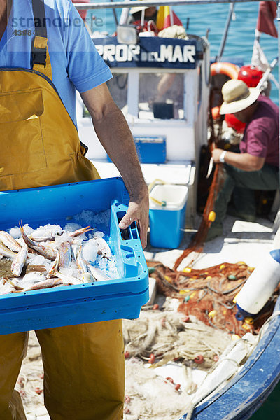 Fischer hält Schale mit frischem Fisch