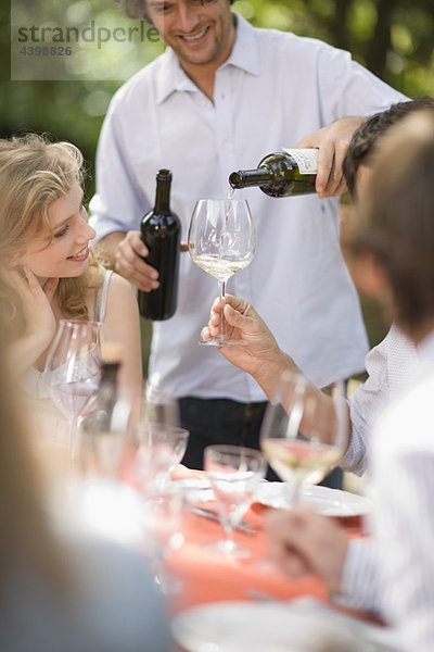 Mann gießt Wein in Gläser