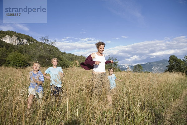 Frau und Jungen  die über ein Feld rennen.