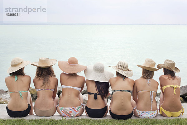 Frauen sitzen am See im Bikini