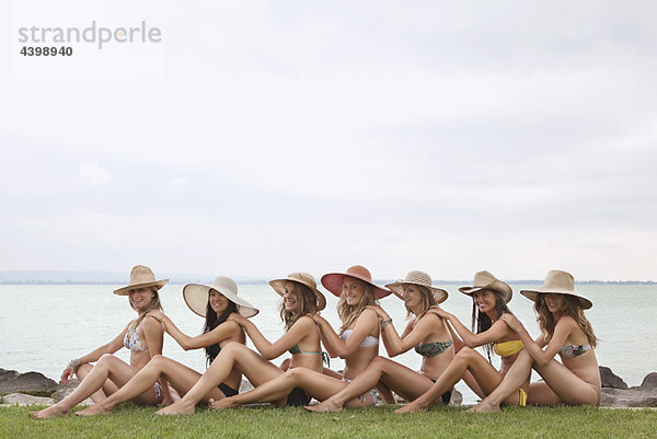 Frauen sitzen in Menschenkette am See