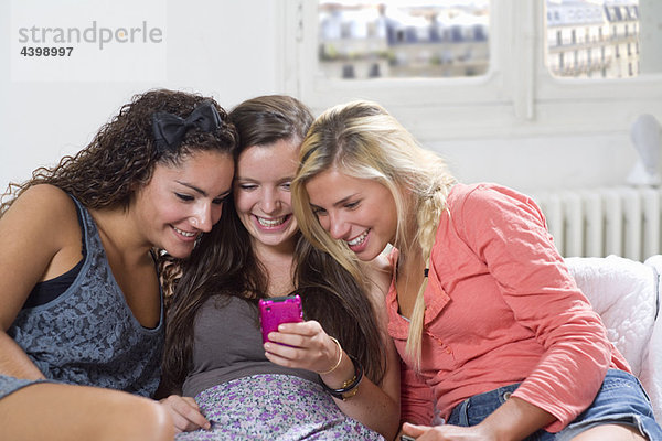 Junge Frauen teilen sich den Telefontext auf der Couch.