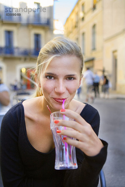 Portrait junge Frau mit Getränk im Café