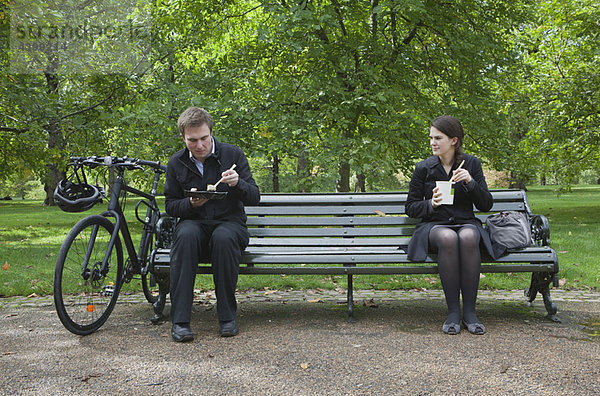 Frau und Mann beim Mittagessen auf der Parkbank