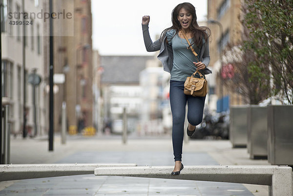Junge Frau beim Springen auf der Straße