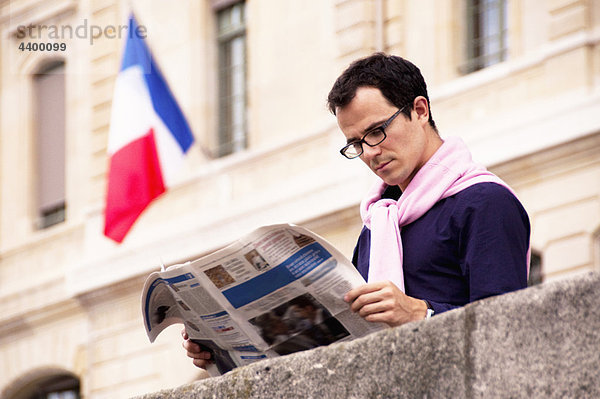 Mann liest Zeitung in Paris