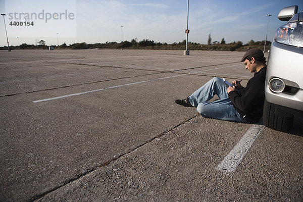 Mann beim Schreiben auf dem Parkplatz