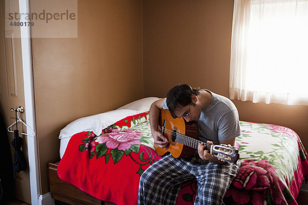 Mann Bett Gitarre spielen