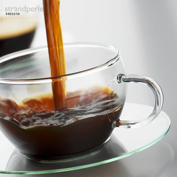 Kaffee in eine Tasse Glas gießen