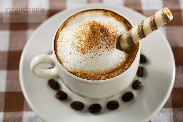 Eine Tasse Cappuccino Wafer Brote und Kaffeebohnen