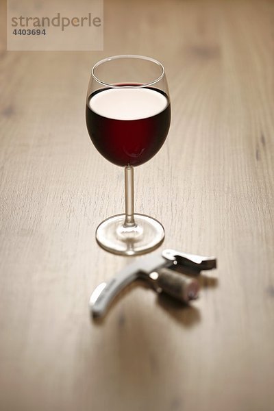 Ein Glas Rotwein mit Korkenzieher und Kork