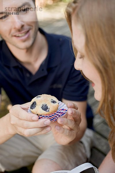 Mann Übergabe Frau ein Heidelbeer-muffin