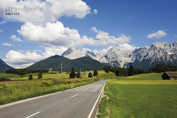 Deutschland  Bayern  Blick auf leere Straße mit Karwendelgebirge im Hintergrund